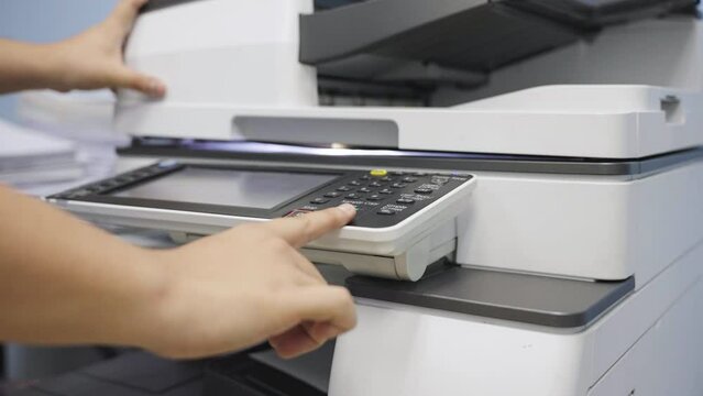 Hands of a male office worker using a photocopier or placing a sheet of paper in the copying machine to copy documents.