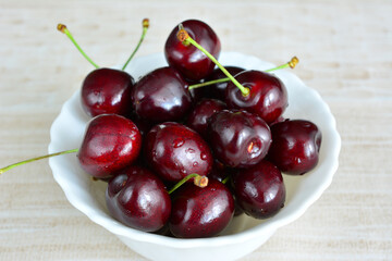 fresh wet dark red cherries in white bowl, close-up