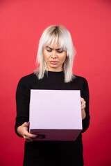 Naklejka premium Young woman with present on a red background