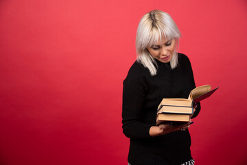 Young woman holding books on a red background