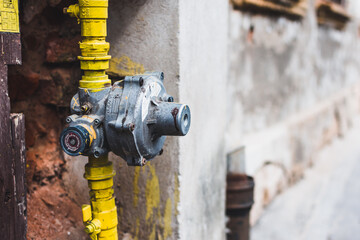 Yellow gas pipeline with pressure regulator next to an old building