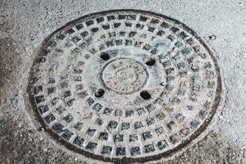 Dirty round metallic sewer cap of a manhole in an urban area