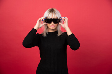 Portrait of woman wearing a black glasses on a red background