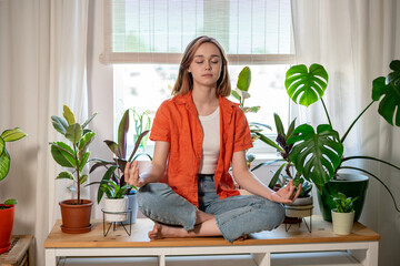 Young female freelancer meditate at workplace in lotus position, feeling zen, no stress, calm concept.