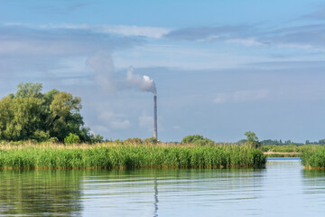View of fuming chimney of the chemical plant at Police over the calm water of Szczecin Bay.
