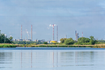 Fuming chimneys of the chemical plant at Police over the calm water of Szczecin Bay.