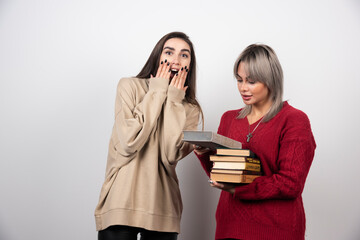 Girl in red sweater reading a book near another girl