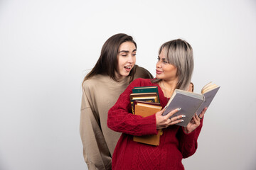 Two friends holding and reading books on a white background