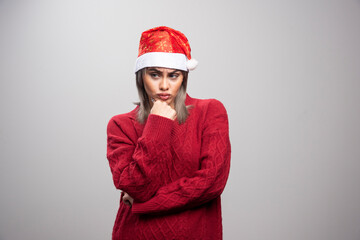 Woman in Santa hat standing angrily on gray background