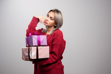 Portrait of sad woman holding gift boxes on gray background