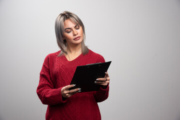 Young businessman looking at clipboard on gray background