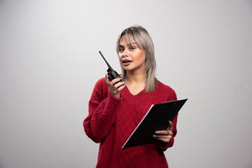 Young female talking with radio transceiver and looking at camera