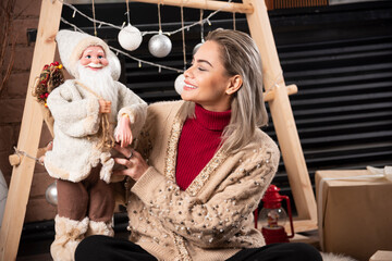Fototapeta na wymiar Portrait of young woman sitting and posing with a Santa Claus toy