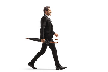 Full length profile shot of a businessman walking and carrying an umbrella