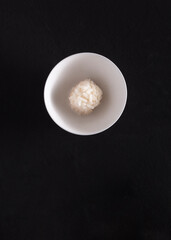 White bowl with portion of sushi rice on a black background
