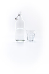 Glass and Clear glass bottle half filled with water on a white background