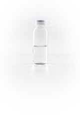 Clear glass bottle half filled with water on a white background