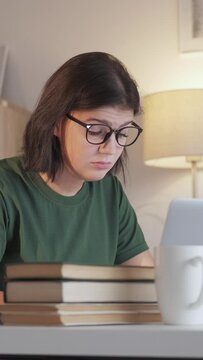 Vertical video. Student fatigue. Internet research. Distance education. Tired overworked woman working online typing using laptop at home workplace.