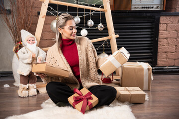 Beautiful young woman looking at her Christmas gifts at home