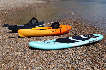 Three canoes rest on the edge of the shingle beach at the mouth of the river Axe in Axmouth