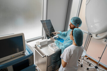 Doctor and nurse in uniform look and discuss an X-ray or MRI scan of the patient spine