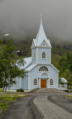 Fototapeta na wymiar Typisch kleine, romantische Kirche in isländische Kleinstadt. Bewölkter Sommertag