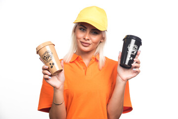 Female courier holding two cups of coffees on white background