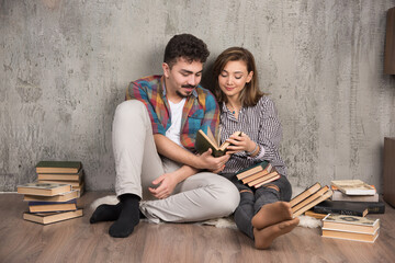 Obraz premium Photo of young couple sitting on the floor and reading a book