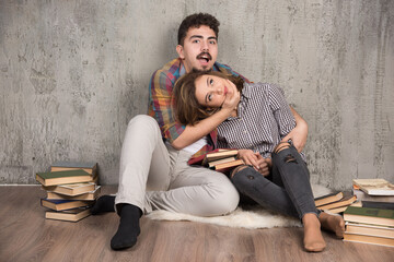 Obraz premium Photo of young couple playfully fighting with each other next to books