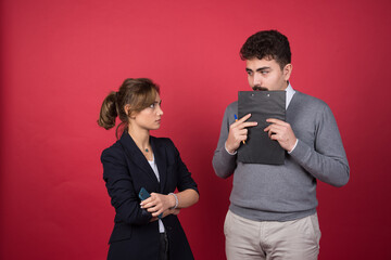 Serious woman looking at man with a clipboard angrily