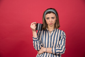Young woman holding cup of coffee with sad expression
