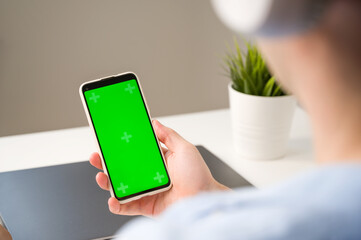 Modern aplications mickup.Smartphone with green chroma screen in hands of unrecognizable man