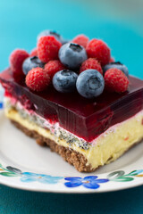 A piece of cake with poppy seeds and berry jelly, cake on a plate decorated with juicy raspberries and blueberries