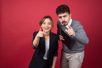 Smiling woman with serious man pointing at camera