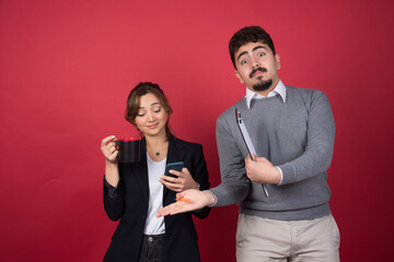 Young woman with cup of drink looking at phone near young man with a clipboard