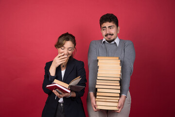 Young man holding a stack of books and young woman reading