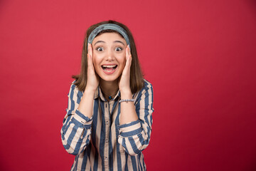 Naklejka premium Adorable girl smiling widely and holding her face