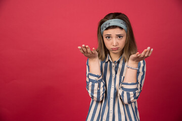 Adorable girl standing on red background with open hands