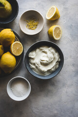 vista superior de cuencos con limones, yogur griego, azúcar y ralladura de limón, para la...