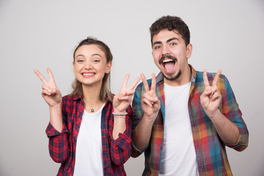 Beautiful couple together wearing plaid shirt over smiling with happy face doing victory sign