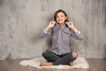 Photo of a smiling young woman sitting and holding her plaid t-shirt