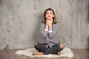 Image of a young woman sitting and holding hands on neck