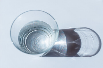 Water glass with sun shadows on white background.Sunlight through glass.Top view.