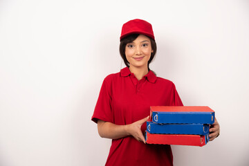 Pretty female pizza delivery worker holding three cardboards of pizza