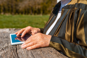 Hands of senior woman holding tablet PC, outdoors in warm summer day.Close up.Selective focus.