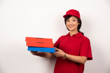 Happy female pizza delivery worker holding three cardboards of pizza