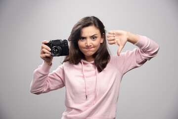 Female photographer holding camera and giving thumbs down