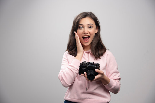 Female photographer posing with camera on gray background
