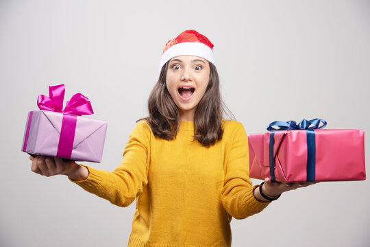 Young woman in Santa hat holding gift boxes and feeling happy
