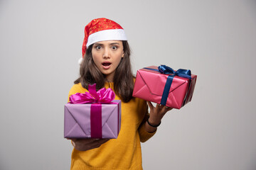 Young woman in Santa hat holding in hands Christmas presents